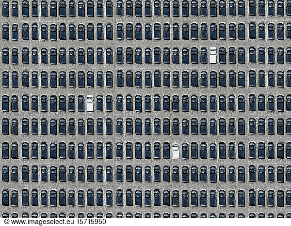 Luftaufnahme von drei weißen Autos  die zwischen ausschließlich schwarzen Autos geparkt sind