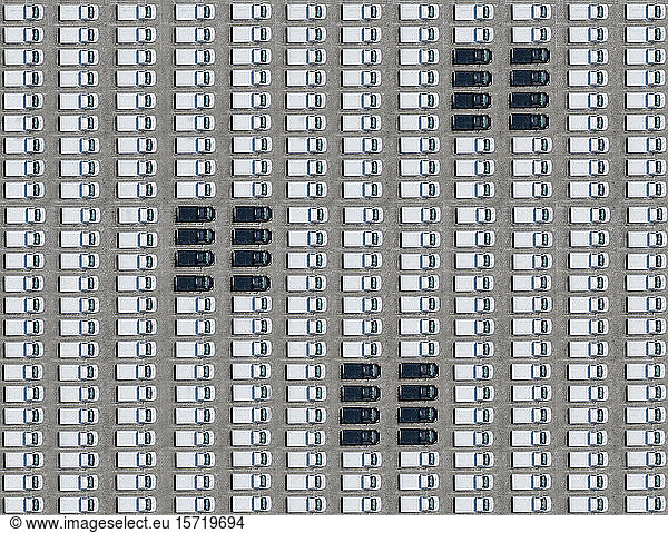Luftbild von wenigen schwarzen Autos  die zwischen ausschließlich weißen Autos geparkt sind