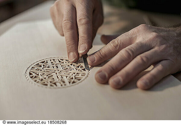 Lute manufacturer carving out ornament out of wood