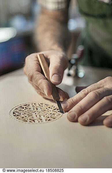 Lute manufacturer carving out ornament out of wood