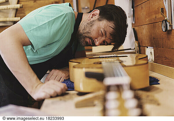 Luthier examining guitar in workshop