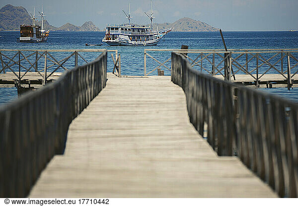 Luxury vessels moored off the coast and viewed from a wooden pier  Komodo National Park; East Nusa Tenggara  Indonesia