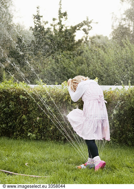 Mädchen beim Spielen mit Rasensprinkler