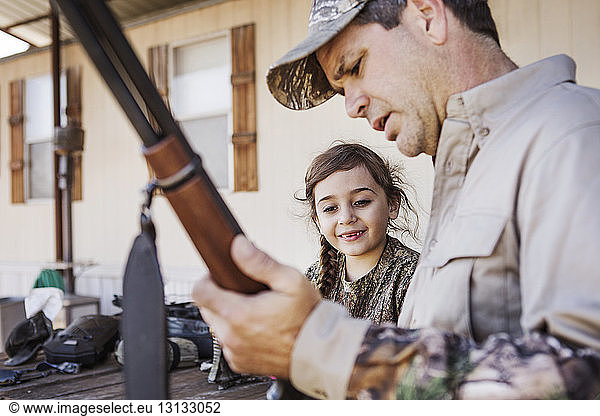 Mädchen beobachtet Vater mit Gewehr in der Hand