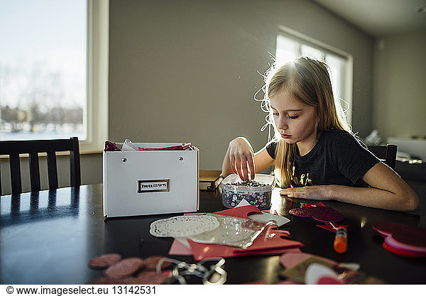 Mädchen bereitet Kunstwerke vor  während sie am Tisch sitzt
