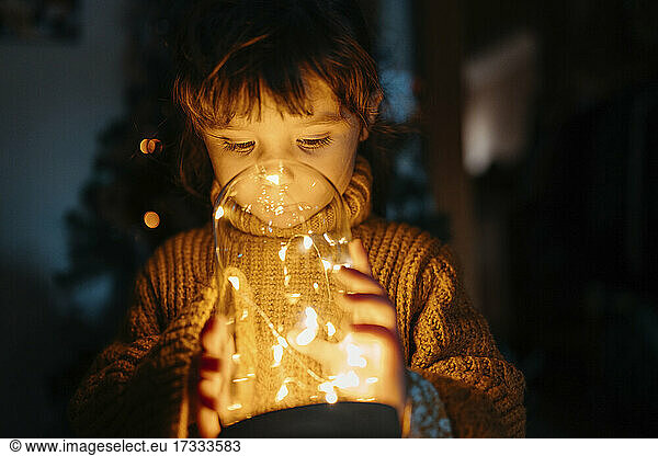 Mädchen betrachtet Weihnachtsdekoration Lichter in der Dunkelheit zu Hause