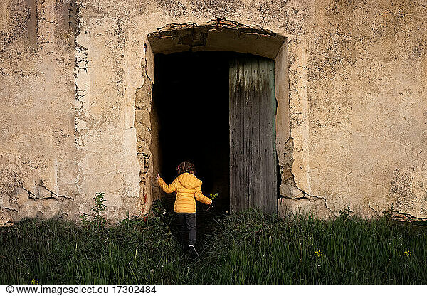 Mädchen blickt in die Tür einer alten Steinscheune in einem Weinberg in Frankreich