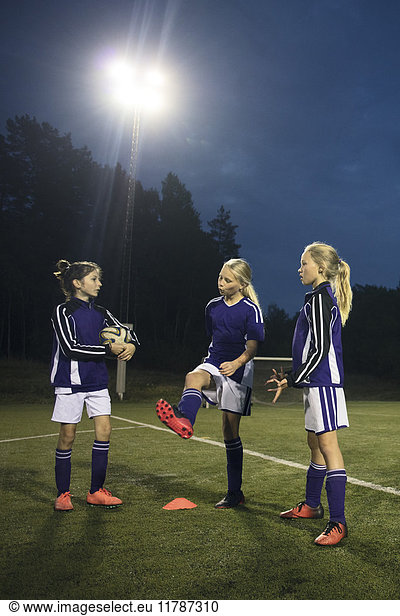 Mädchen  die nachts auf dem Fußballfeld gegen den Himmel stehen.