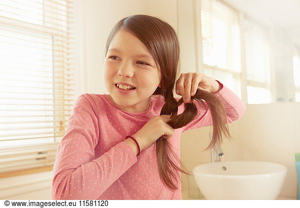 Mädchen flechtet langes braunes Haar im Badezimmer