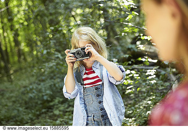 Mädchen fotografiert im Wald mit einer altmodischen Kamera