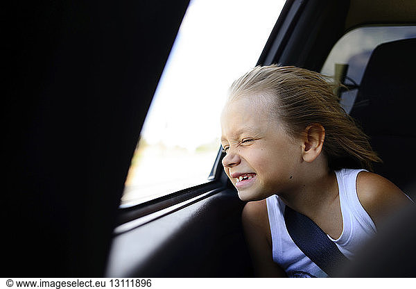 Mädchen genießt Wind  während sie im Auto am Fenster sitzt