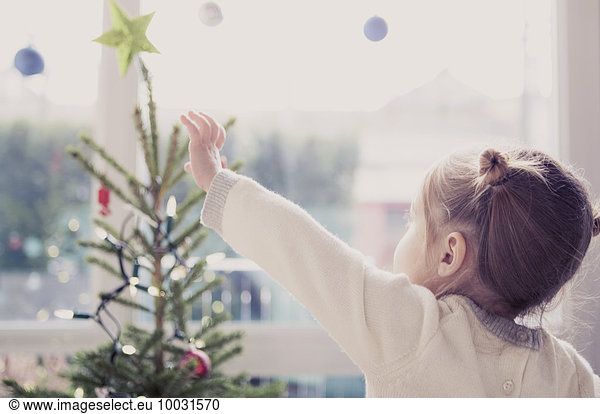 Mädchen greift nach dem Start am Weihnachtsbaum