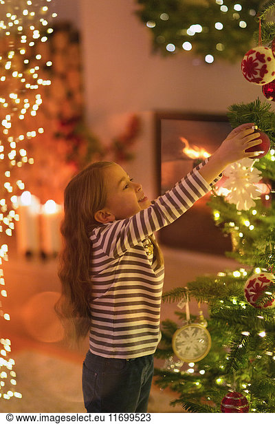 Mädchen hängt Ornament an Weihnachtsbaum
