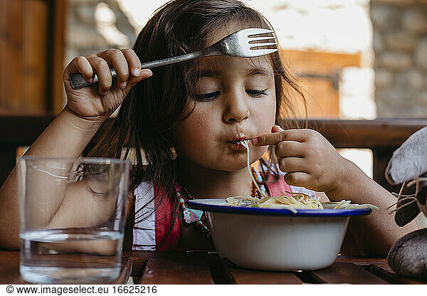 Mädchen isst Essen  während sie zu Hause am Tisch sitzt