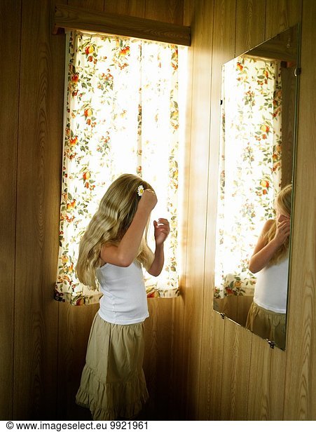Mädchen kämmt lange blonde Haare im Schlafzimmer Spiegel