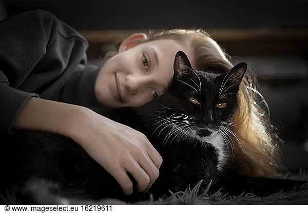 Mädchen kuschelt mit schwarzer Katze