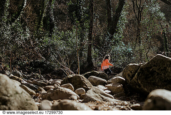 Mädchen läuft durch riesige Felsen im Wald auf dem Lande
