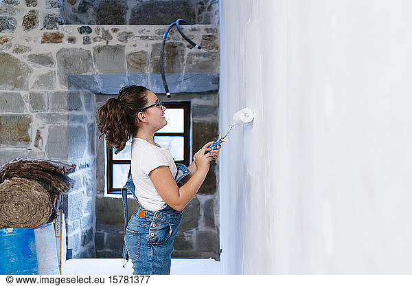 Mädchen malt eine Wand in einem Haus