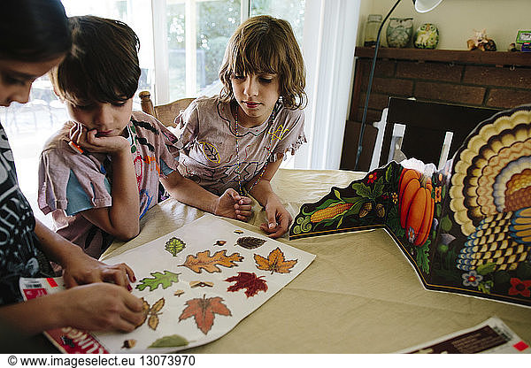 Mädchen mit Geschwistern entfernt Blätteretiketten am Tisch