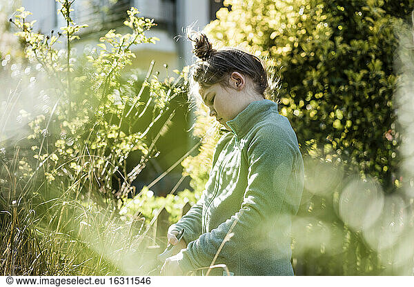Mädchen mit Handgerät bei der Gartenarbeit im Garten
