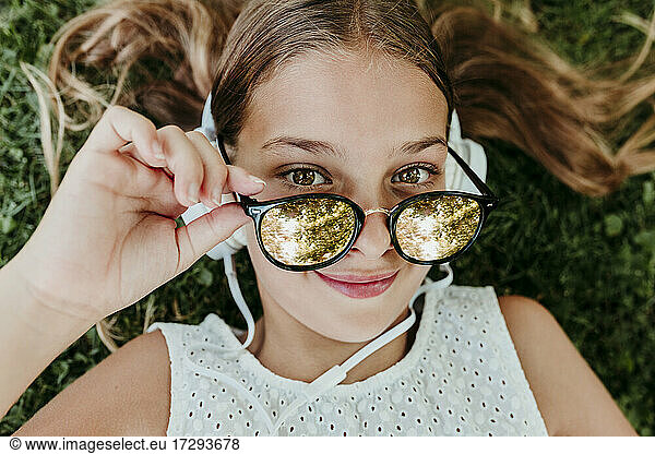 Mädchen mit Sonnenbrille im Gras liegend