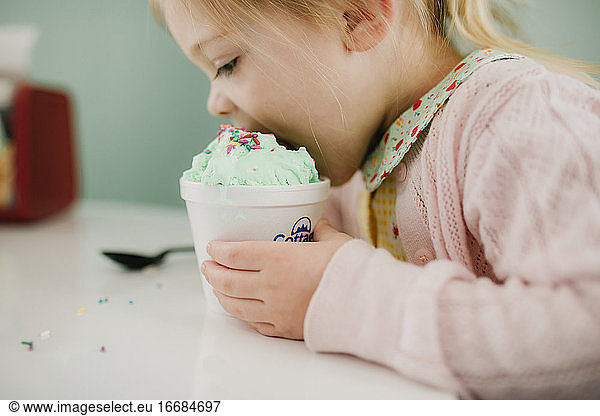 Mädchen nimmt einen großen Bissen von ihrem grünen Eis
