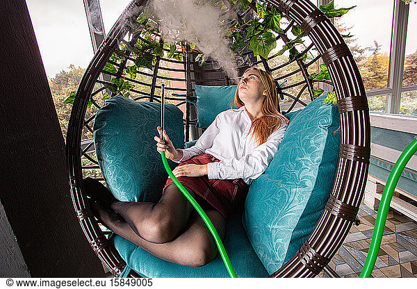 Mädchen raucht Wasserpfeife in einem Holzstuhl