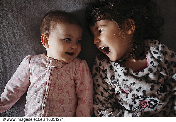Mädchen schreit beim Anblick der süßen kleinen Schwester auf dem Bett