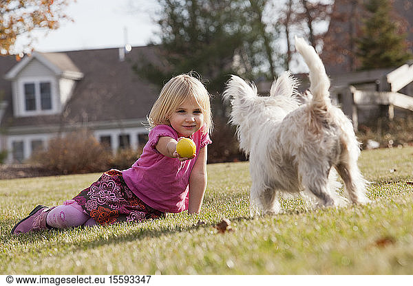 Mädchen spielt Ball mit Haustier Terrier