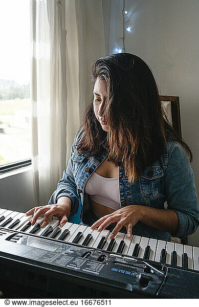 Mädchen spielt Klavier in ihrem Zimmer Hobby
