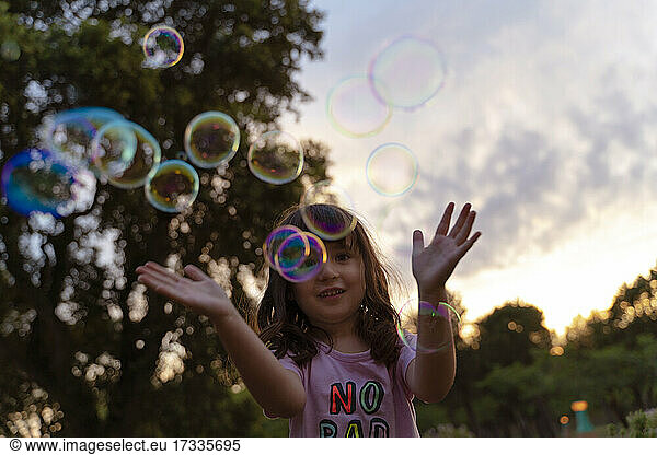 Mädchen spielt mit Seifenblasen bei Sonnenuntergang