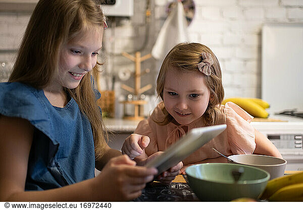 Mädchen spielt Spiel auf Tablet mit Schwester