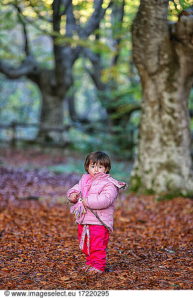 Mädchen steht auf Herbstblättern im Naturpark Gorbea