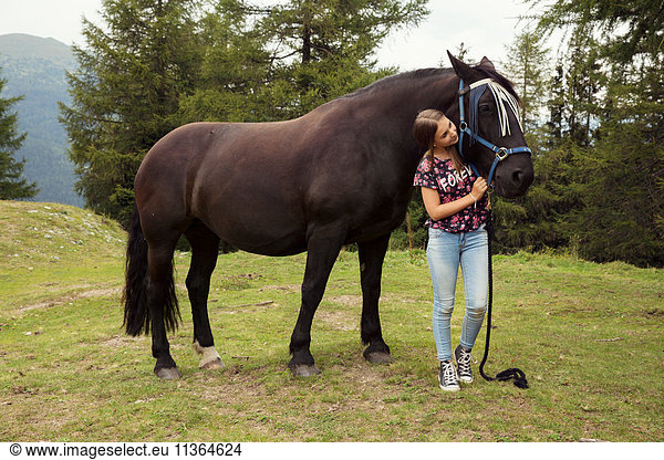 Mädchen streichelt Pferd in Waldlichtung  Sattelbergalm  Tirol  Österreich