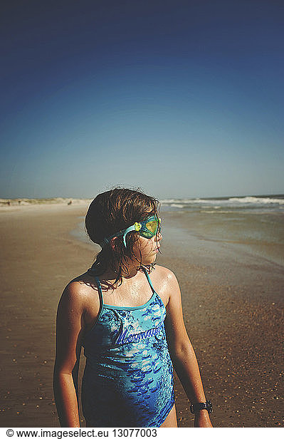 Mädchen trägt eine Schwimmbrille  während sie am Strand von St. Augustine am sonnigen Tag gegen den klaren Himmel wegschaut