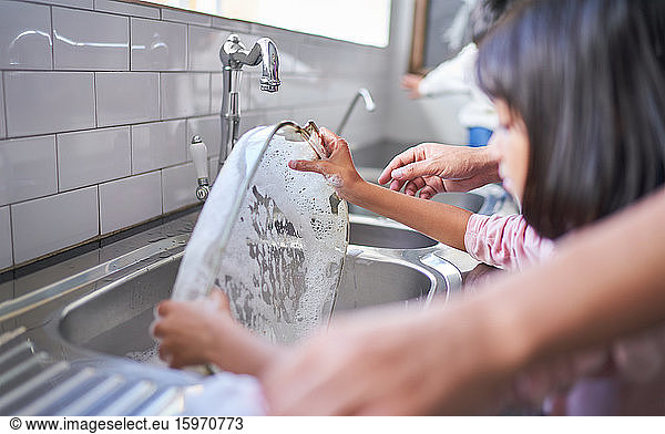 Mädchen wäscht Auflaufform an der Küchenspüle
