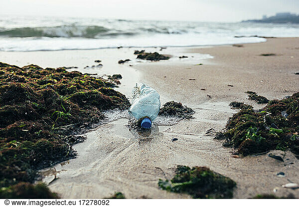 Müll und Wasserflasche am Strand