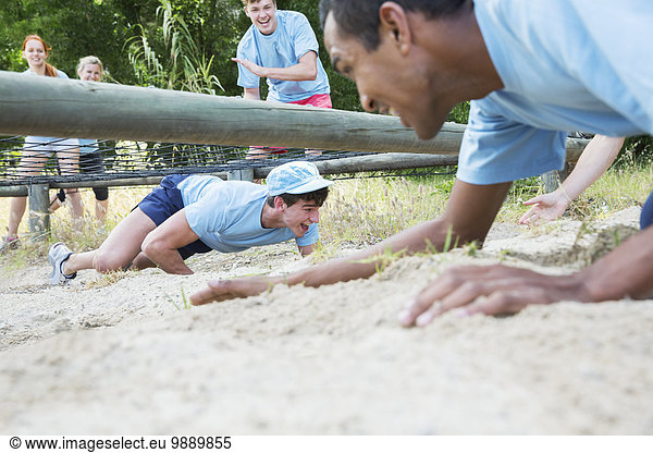 Männer krabbeln unter dem Netz auf dem Boot Camp Hindernisparcours