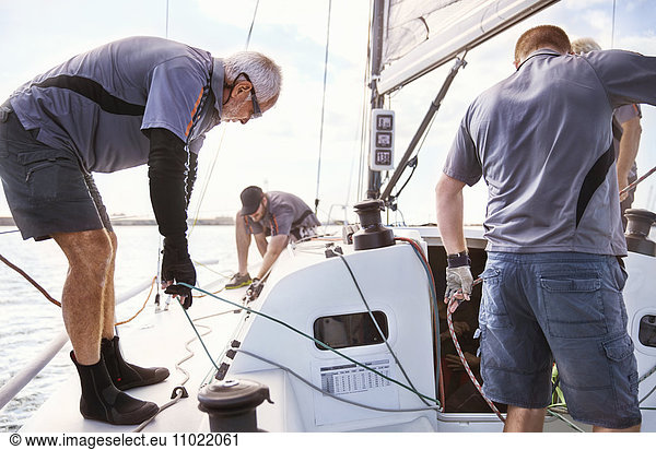 Männer segeln Segelboot Rigg einstellen