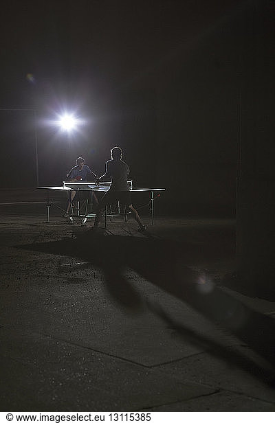 Männer spielen Tischtennis auf beleuchtetem Feld