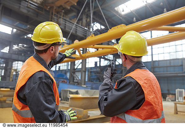 Männliche Arbeiter beobachten die Aufzucht der Ausrüstung in der Fabrik.