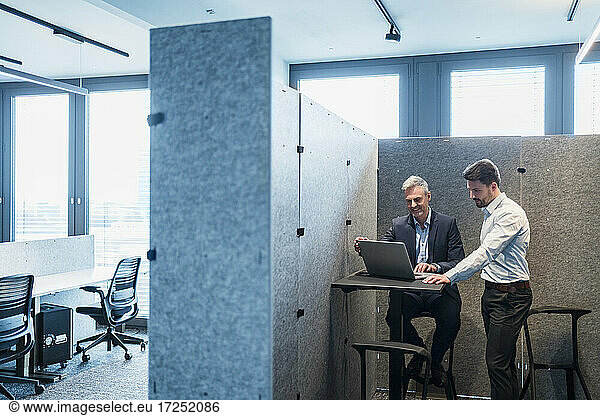 Männliche Fachleute  die in einem Coworking Space über einen Laptop diskutieren