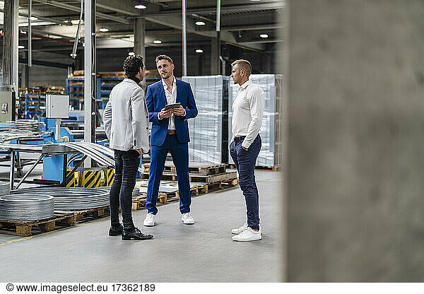 Männliche Fachleute diskutieren in einer Fabrik stehend