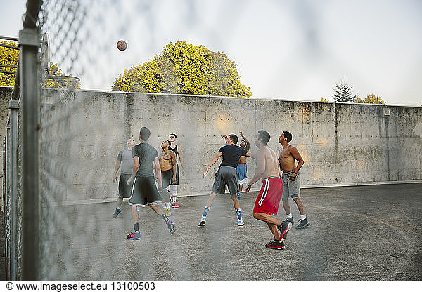 Männliche Freunde üben Basketball vor Gericht