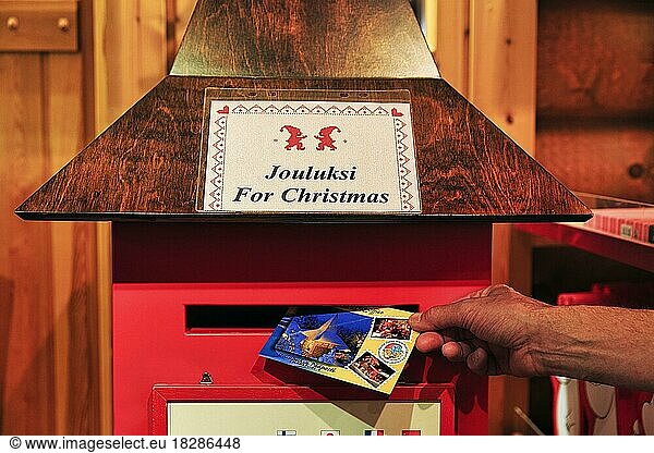 Männliche Hand wirft Weihnachtskarte  Postkarte in Briefkasten  Innenaufnahme  Symbolbild Kommunikation  Nostalgie  Tradition  Weihnachtsmanndorf am Polarkreis  Rovaniemi  Lappland  Finnland  Europa
