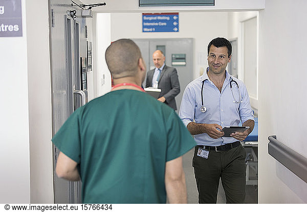 Männliche Ärzte grüßen sich  gehen aneinander vorbei im Krankenhausflur