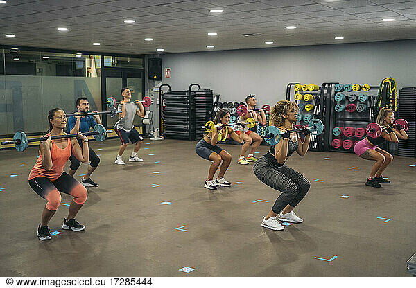 Männliche und weibliche Athleten beim Langhantelheben im Fitnessstudio