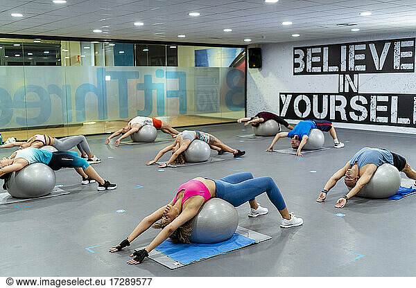 Männliche und weibliche Athleten beim Training mit Fitnessbällen im Fitnessstudio