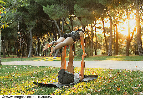 Männliche und weibliche Athleten üben Acroyoga im Park bei Sonnenuntergang