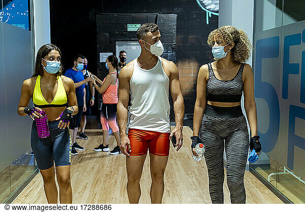 Männliche und weibliche Athleten tragen beim Laufen in der Sporthalle Gesichtsschutzmasken